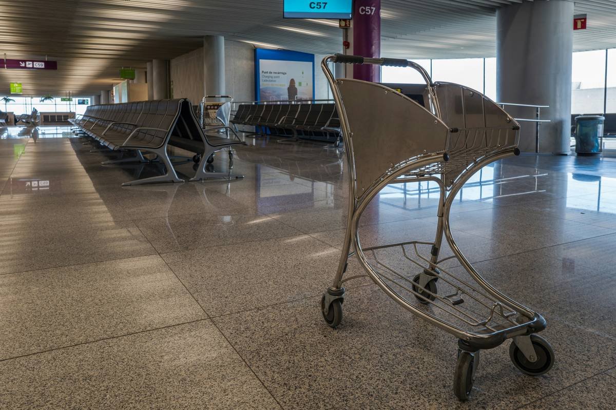 Woman stressed at airport counter holding dog carrier during credit card travel insurance emergency pet quarantine situation